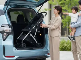 シエンタの開いたバックドアからベビーカーを荷室に入れようとしている日本人夫婦と子供。
