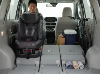 大人の日本人男性がシエンタの3列目シートに座り、足元のスペースが狭く窮屈そうに膝を曲げている様子。