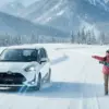 雪道を走る白いトヨタ・シエンタと、その隣で雪山の景色を指差して眺める日本人家族の様子。