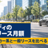 ガラス張りのビルが並ぶ並木道を走る濃いグレーのハッチバック