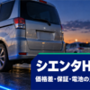 夕方の中古車展示場で青い照明に照らされたコンパクトミニバンの後ろ姿