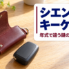 木のテーブルに置かれた黒いスマートキーとレザーのキーケース